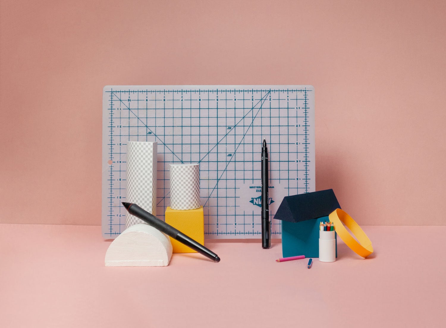 Illustration représentant un tapis de découpe avec des objets de formes géométriques, des crayons, un feutre, ainsi qu’un stylet de tablette graphique.