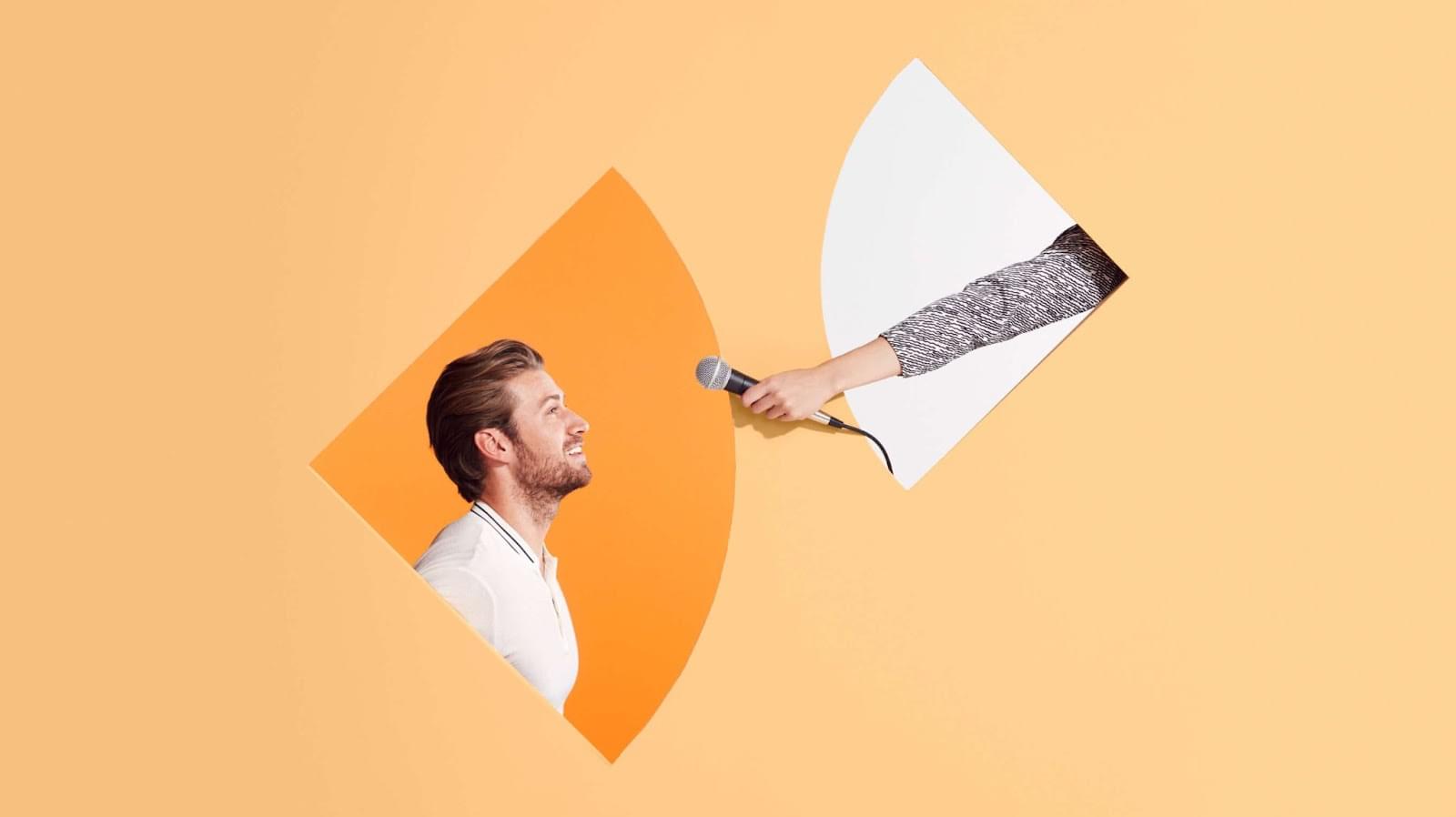 A woman in headphones smiles while typing on her laptop, creating employee engagement survey questions.